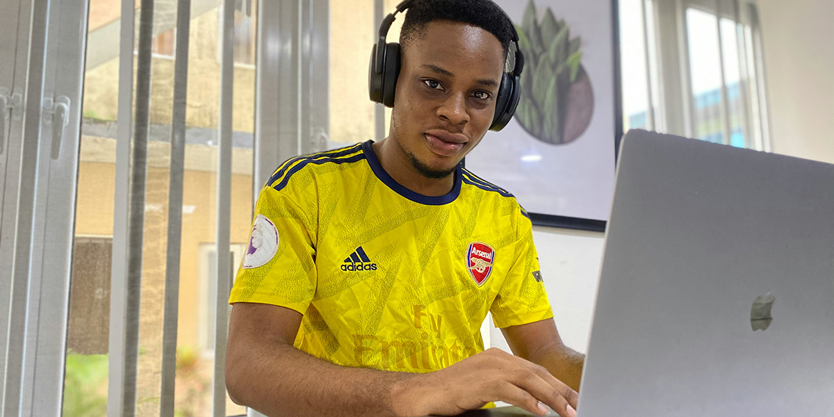 A student wearing headphones working is working on his laptop.