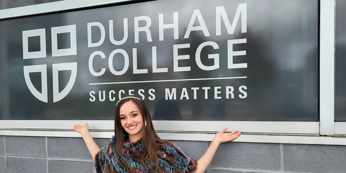 Vikki Pike smiles in front of a Durham College sign.