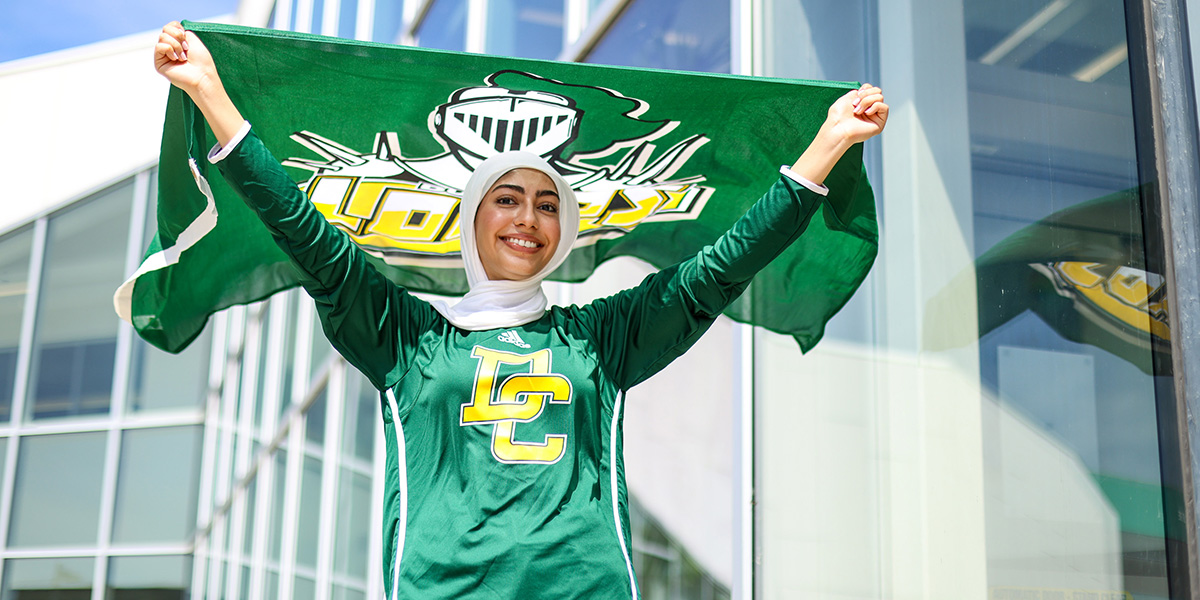 A student holds a DC flag and smiles