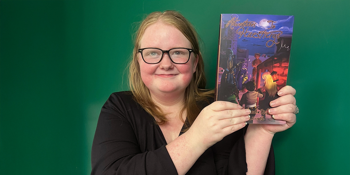 A photo of Cassandra Watt holding a copy of her new novel.