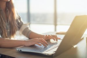 learner sitting at desk typing on laptop