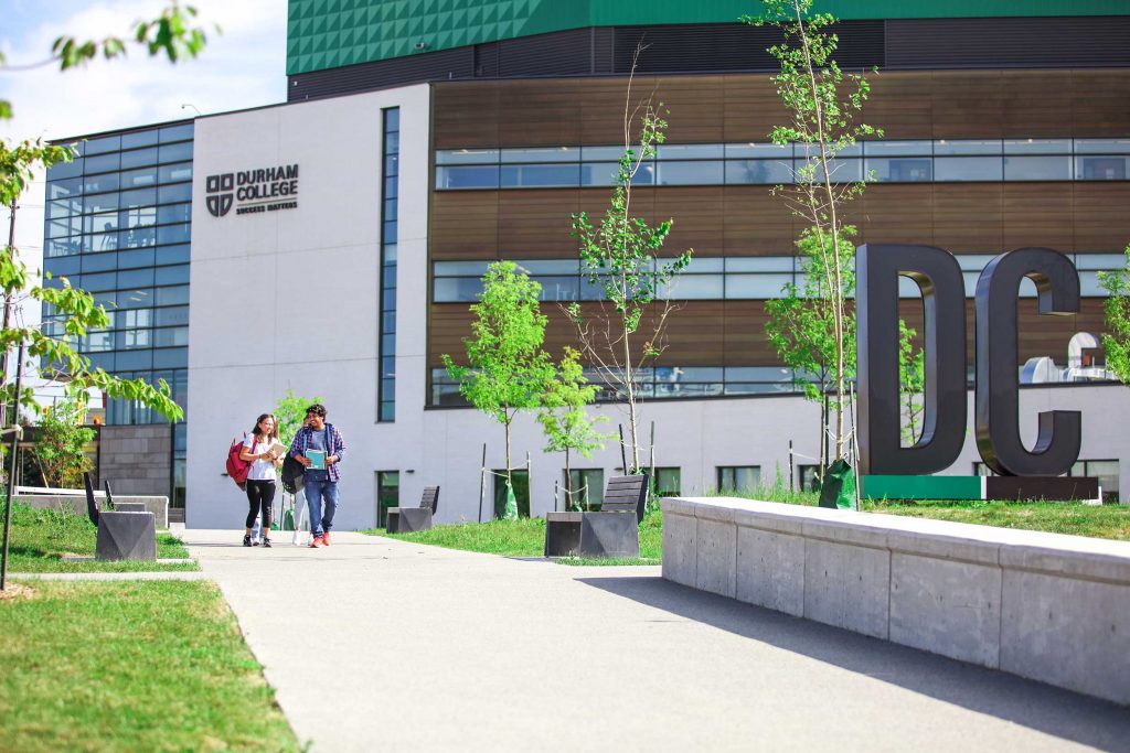 Students walking along the sidewalk over the geothermal field at Durham College
