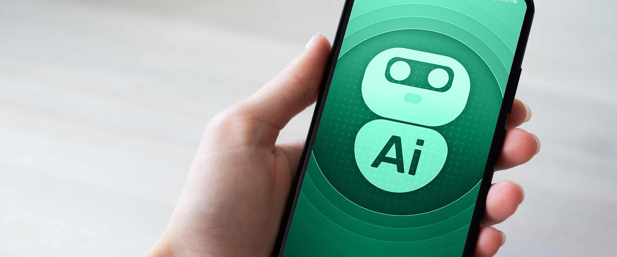 Closeup photo of a smartphone in one's hand with a robot logo and the letters AI appearing on the screen.