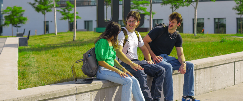 Students sitting outside in the Naanaagide'endamowin Courtyard at Durham College, Oshawa Campus.