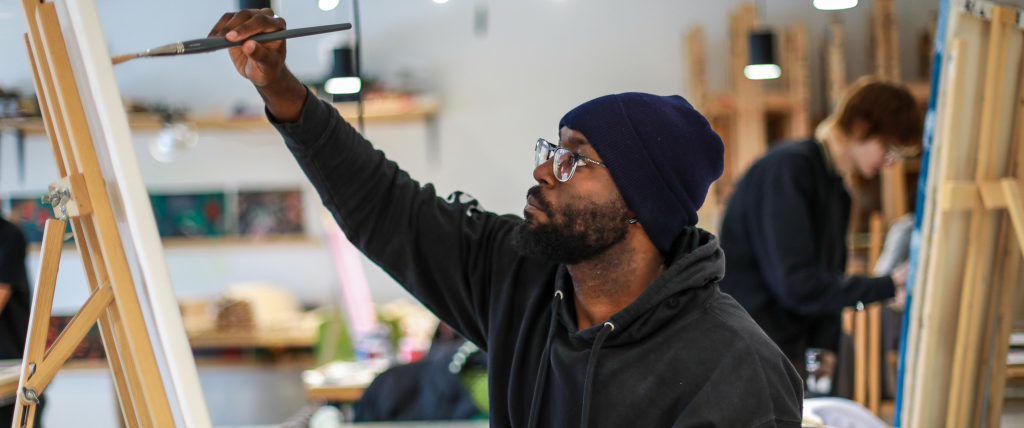 Student painting an easel in an art studio.