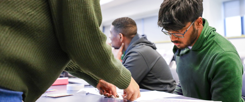 A student getting support by a faculty member in a classroom.