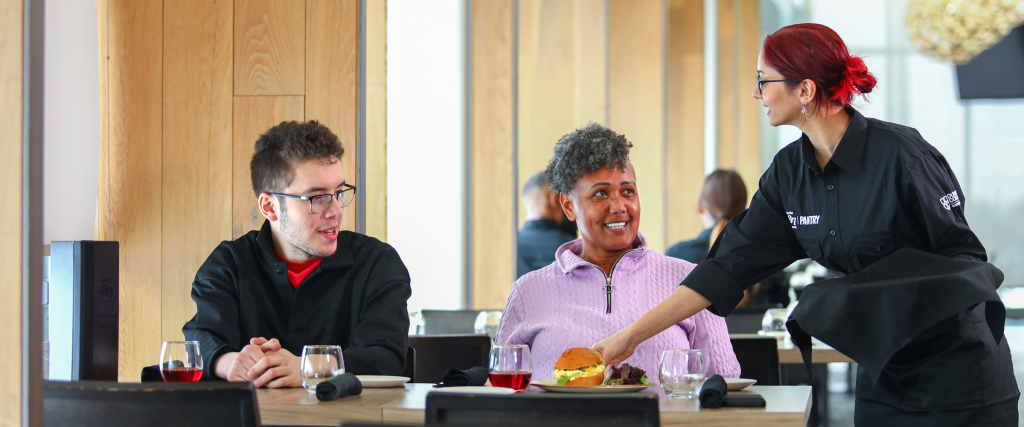 Student wait staff serving customer in Bistro '67.