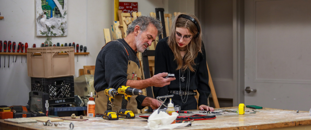 DC faculty member looking at settings on a tool in fabrication class.