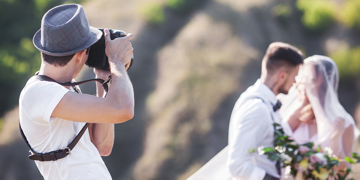 A photographer taking a photo of a groom and bride
