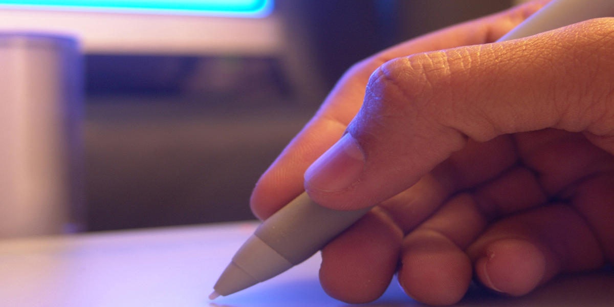 A hand holding a graphics tablet pen