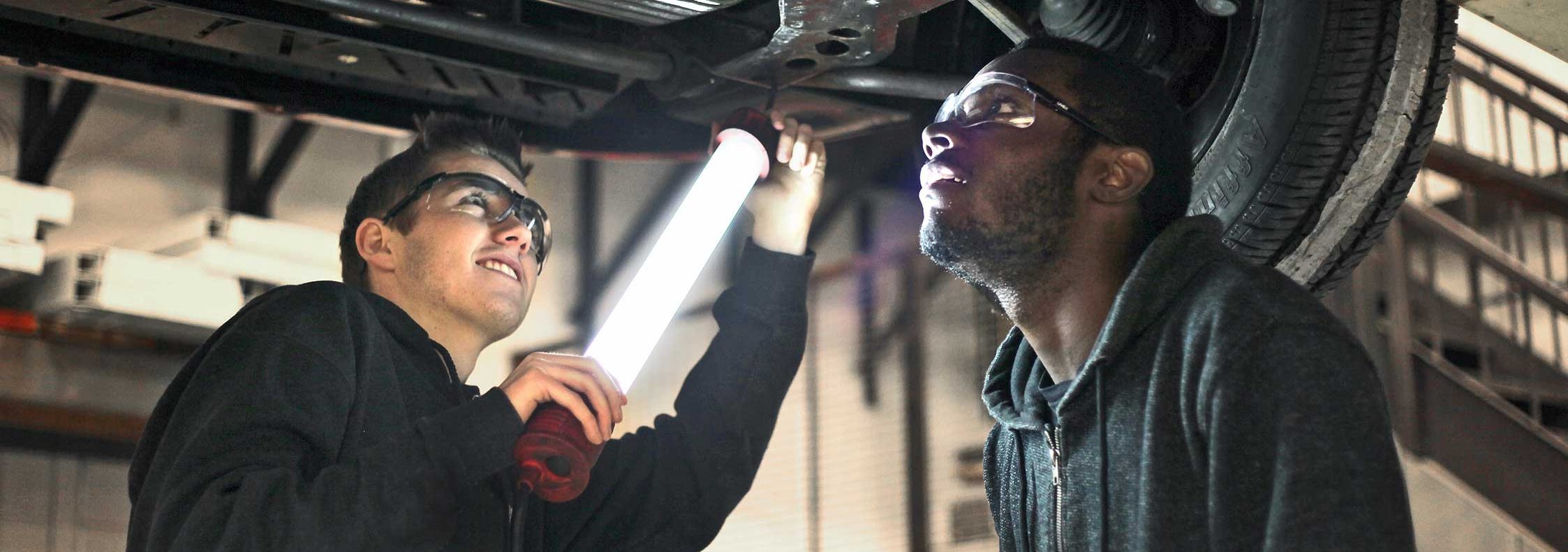 two students working under a car