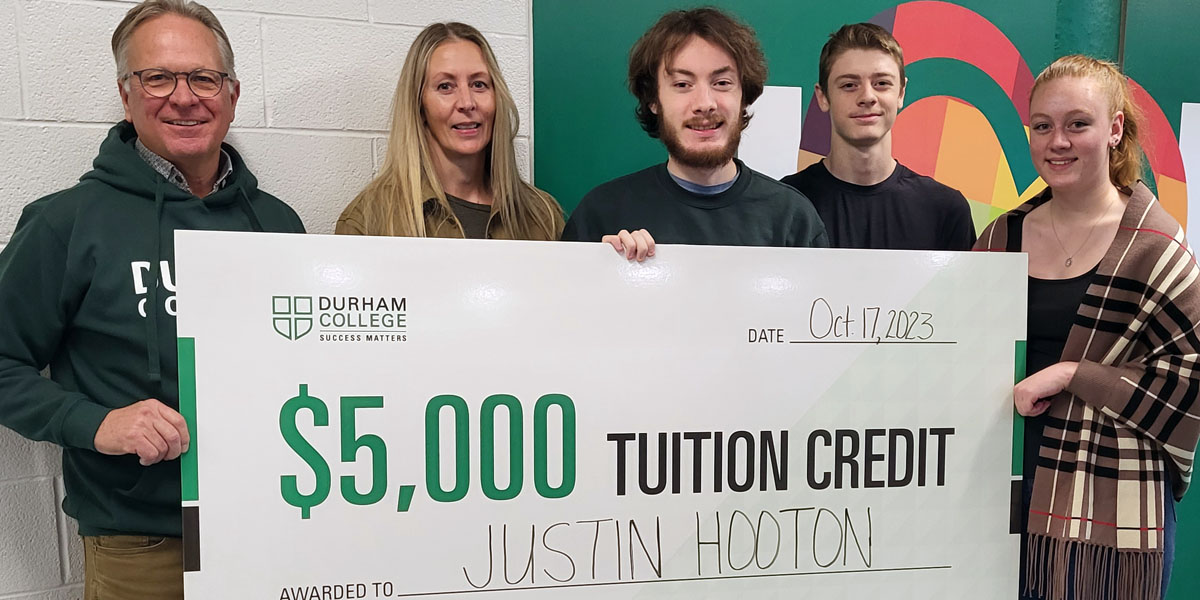 Justin Hooton holds up a big cheque alongside his family and DC president Don Lovisa.