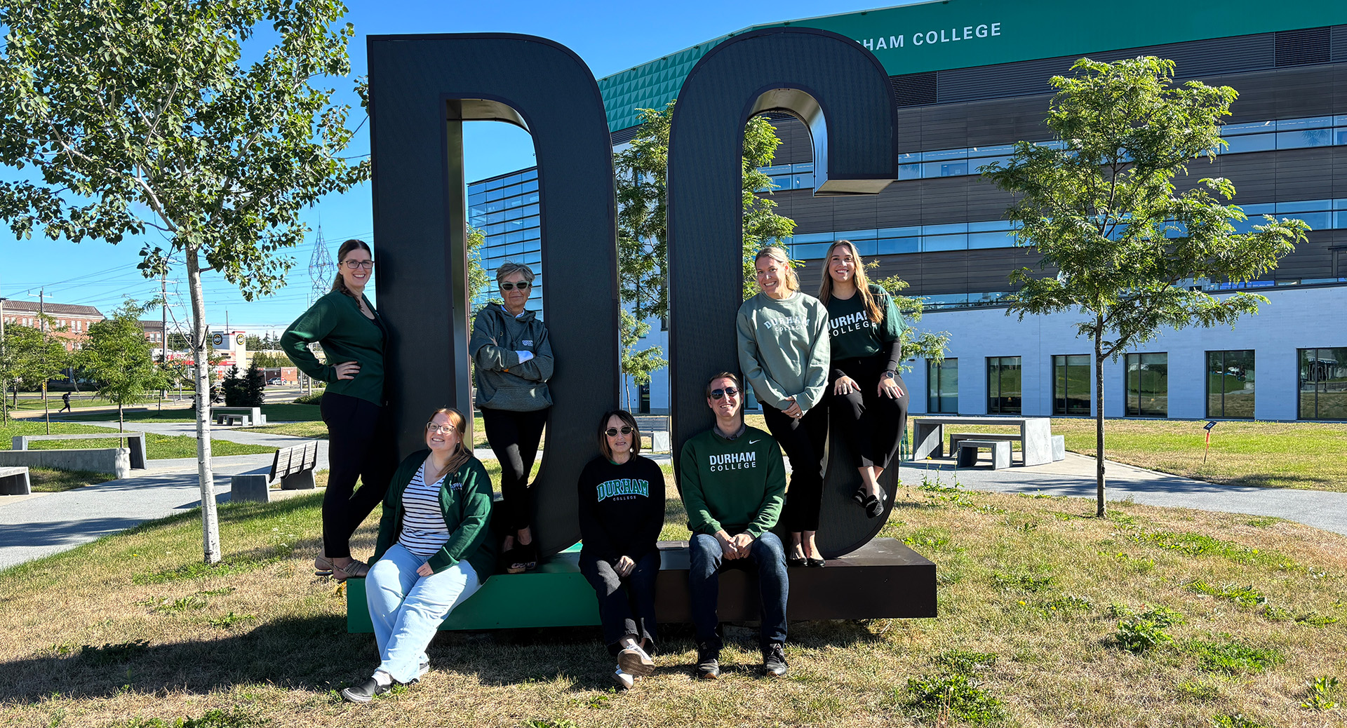 DC's Advancement and Alumni Relations team gathered casually around an outdoor "DC" sculpture for a group photo.