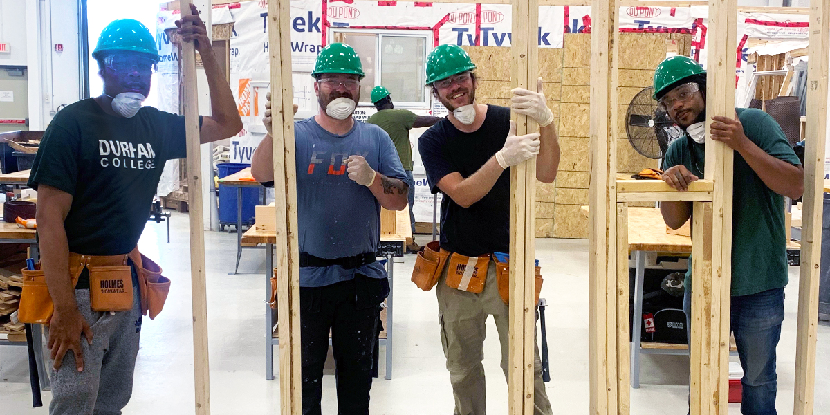 Blue Door Construct participants pose to take a photo while working in Durham College's carpentry shop
