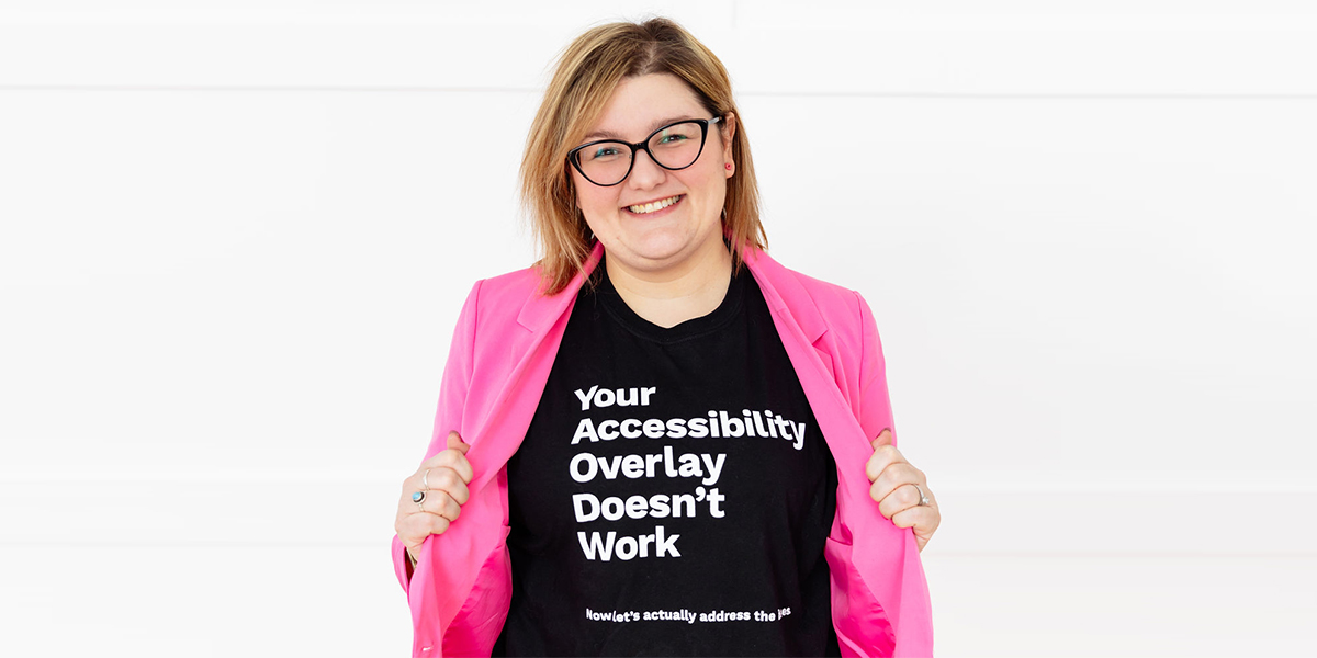 Matisse Hamel-Nelis smiles and displays her shirt with the message 'Your Accessibility Overlay Doesn't Work'.