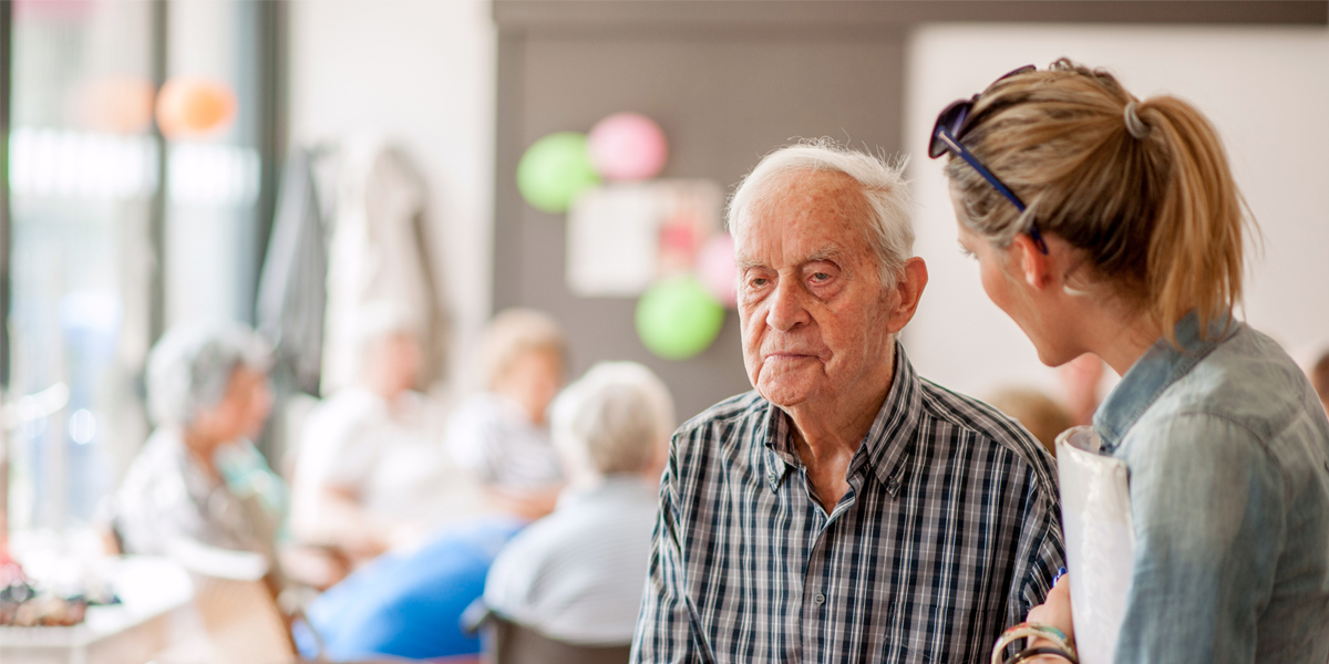 Care practitioner looking toward elderly patient in retirement home