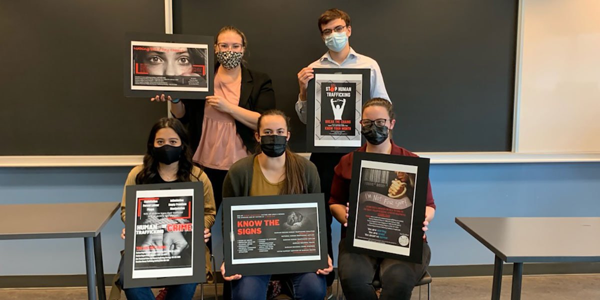 Durham College Global Issues students standing in a group showing off anti-human-trafficking posters