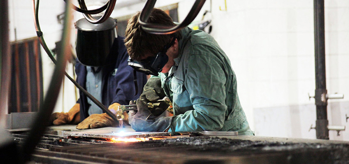 Photo of student(s) using acetylene torch to cut metal, Whitby campus.