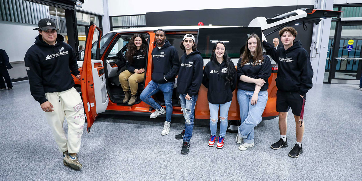 A greenhouse on a greenfield with a woman show inside at a distance.