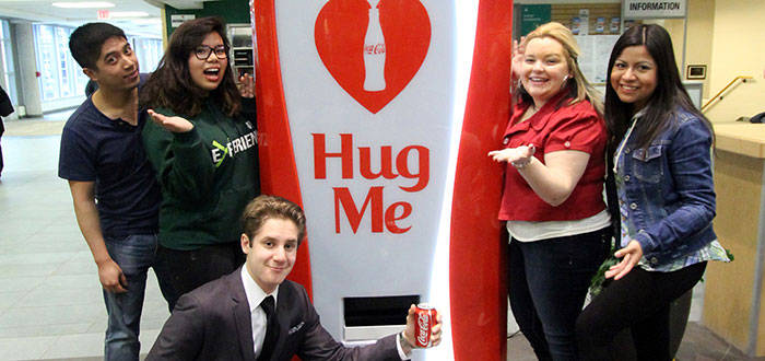 Group of students get a free coke from hug me machine