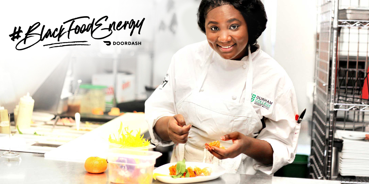 Young black female chef smiles while preparing food