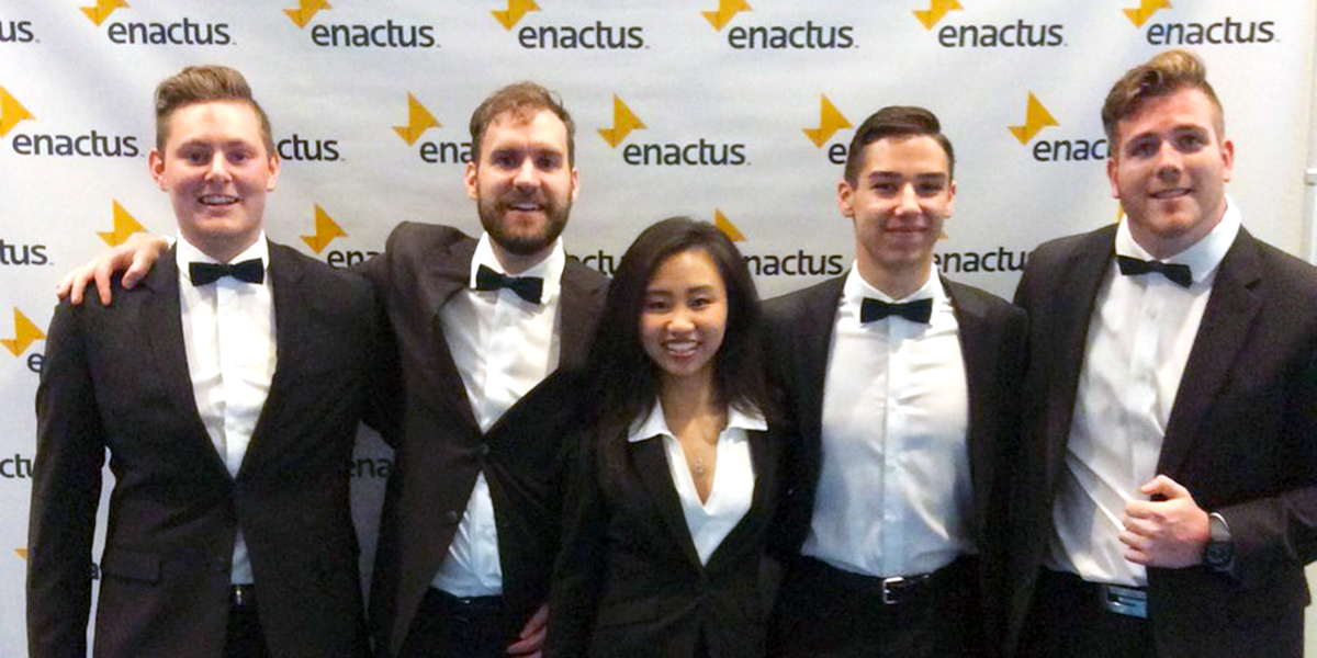 DC students pose for photo in front of Enactus photo wall.