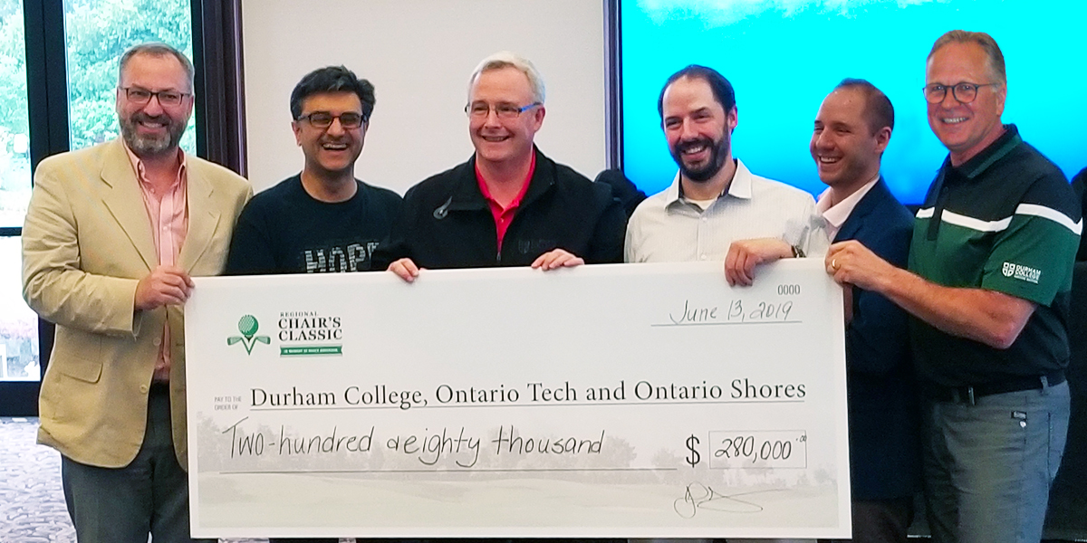 Large cheque of $280,000 raised is held by leadership from Durham College and other institutions that participated in the Regional Chair Classic.