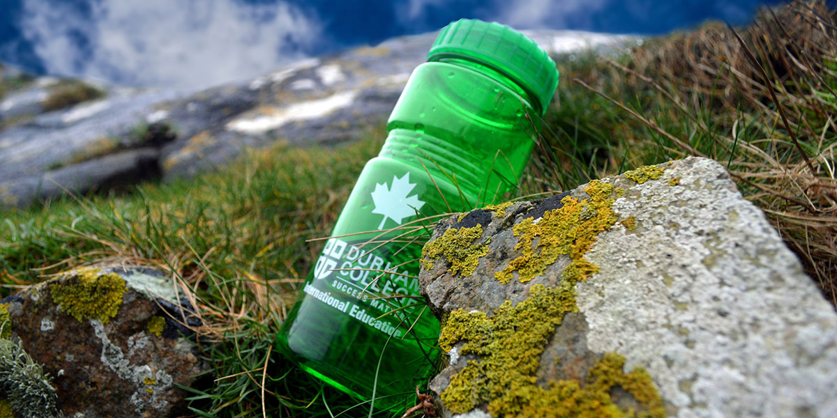 DC branded water bottle among grass and rocks in Ireland.