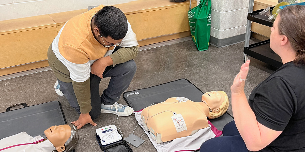 A student and faculty member practice lifesaving techniques.