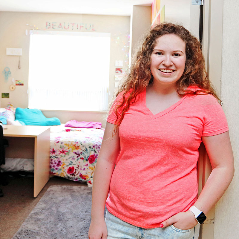 Female resident adviser leaning by a door