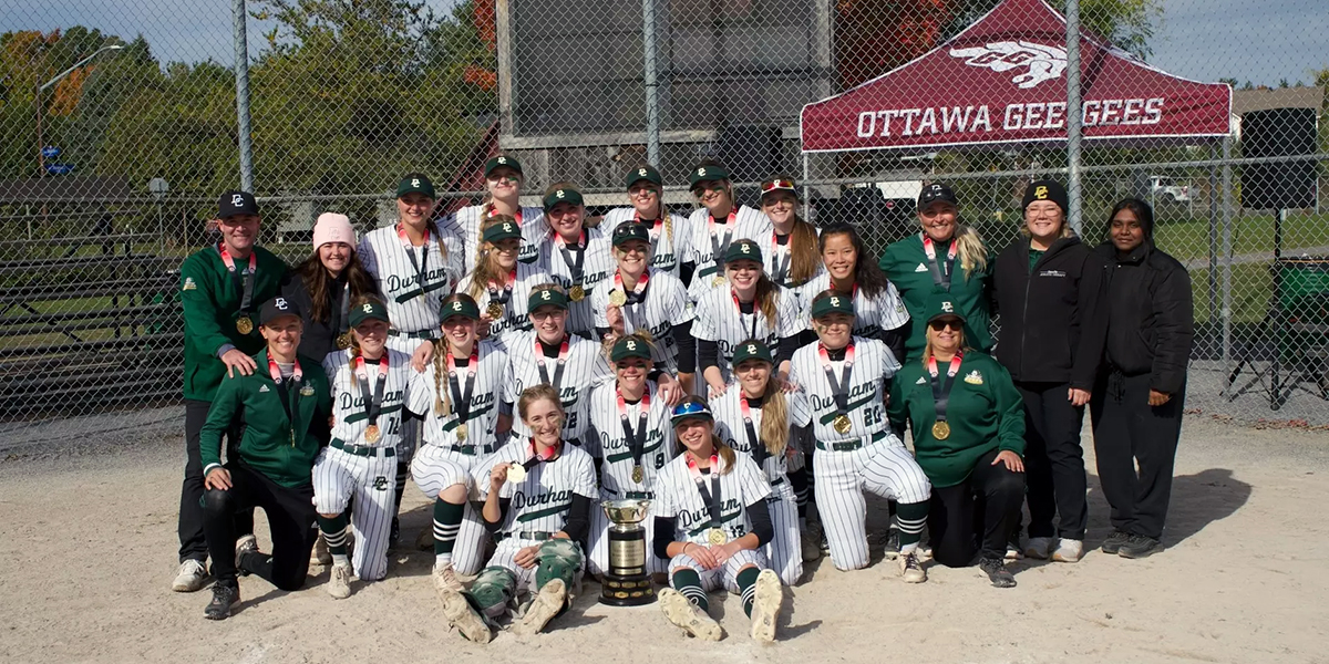 The women's softball team takes a team photo.